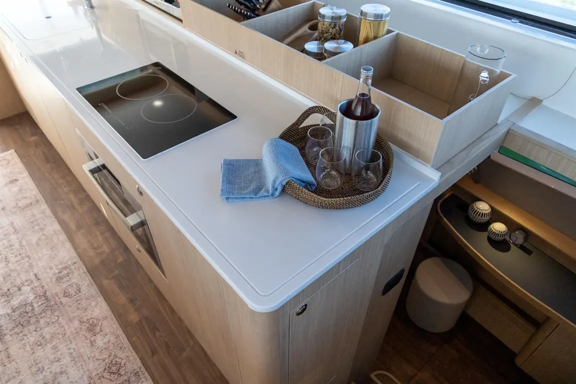 Modern kitchen countertop featuring an induction cooker, a tray with glasses and a bottle, plus a blue cleaning cloth.